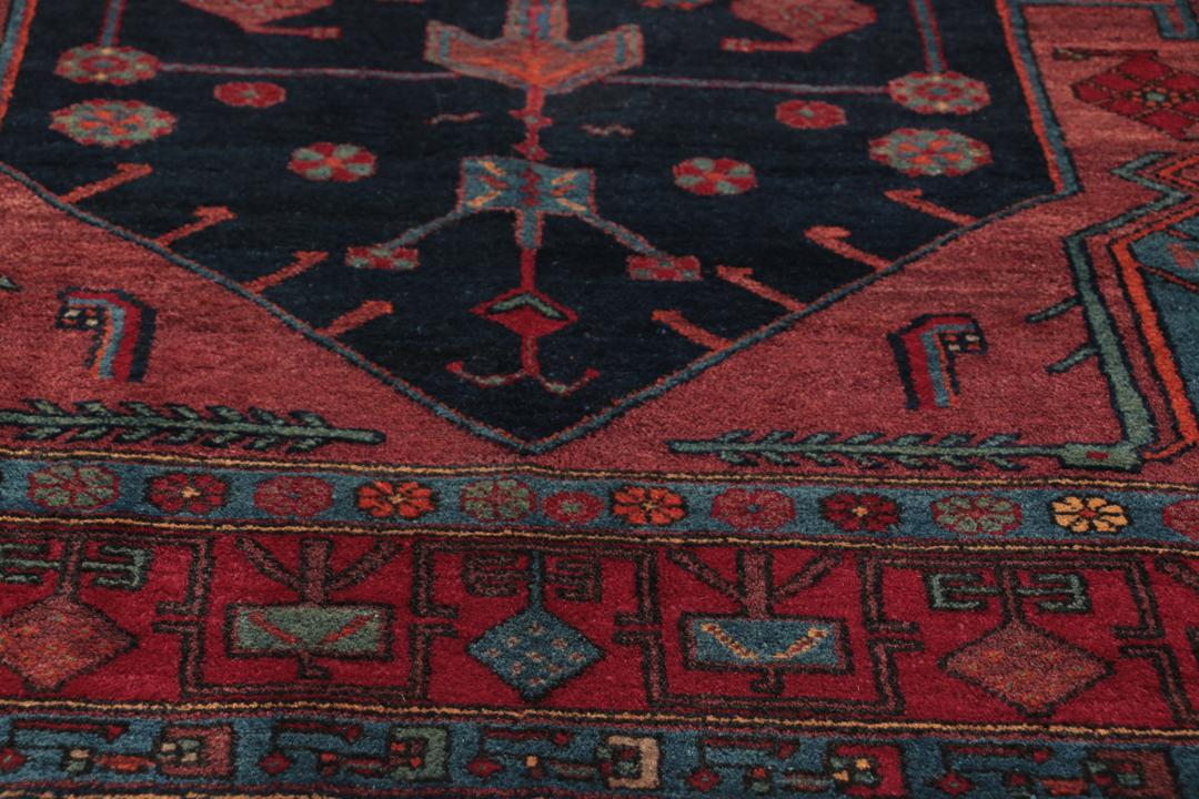 Een handgeknoopt Zanjan-tapijt uit het Midden-Oosten met een donkerblauw en rood geometrisch ontwerp.
