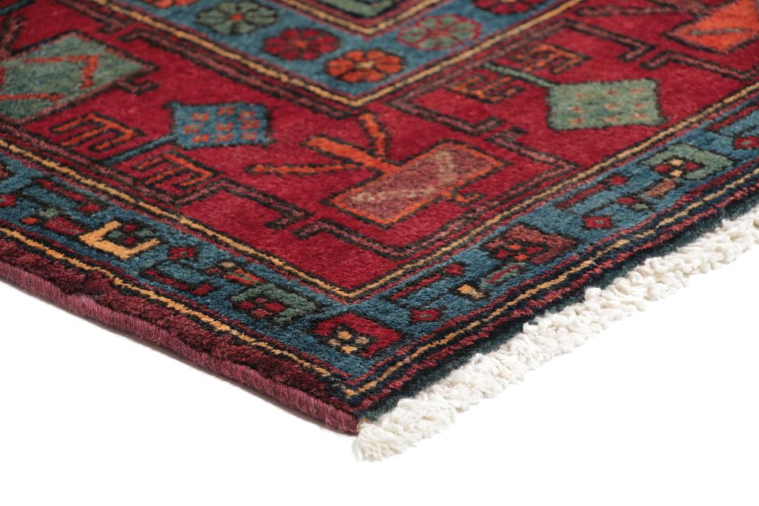 Een handgeknoopt Zanjan-tapijt uit het Midden-Oosten met een donkerblauw en rood geometrisch ontwerp.