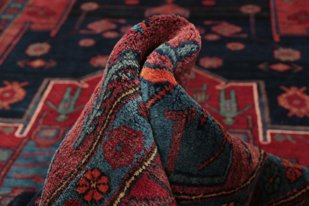 Een handgeknoopt Zanjan-tapijt uit het Midden-Oosten met een donkerblauw en rood geometrisch ontwerp.