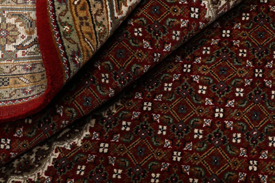 Ręcznie wiązany indyjski dywan Tabriz z dużym centralnym medalionem w odcieniach ciemnej czerwieni i beżu.