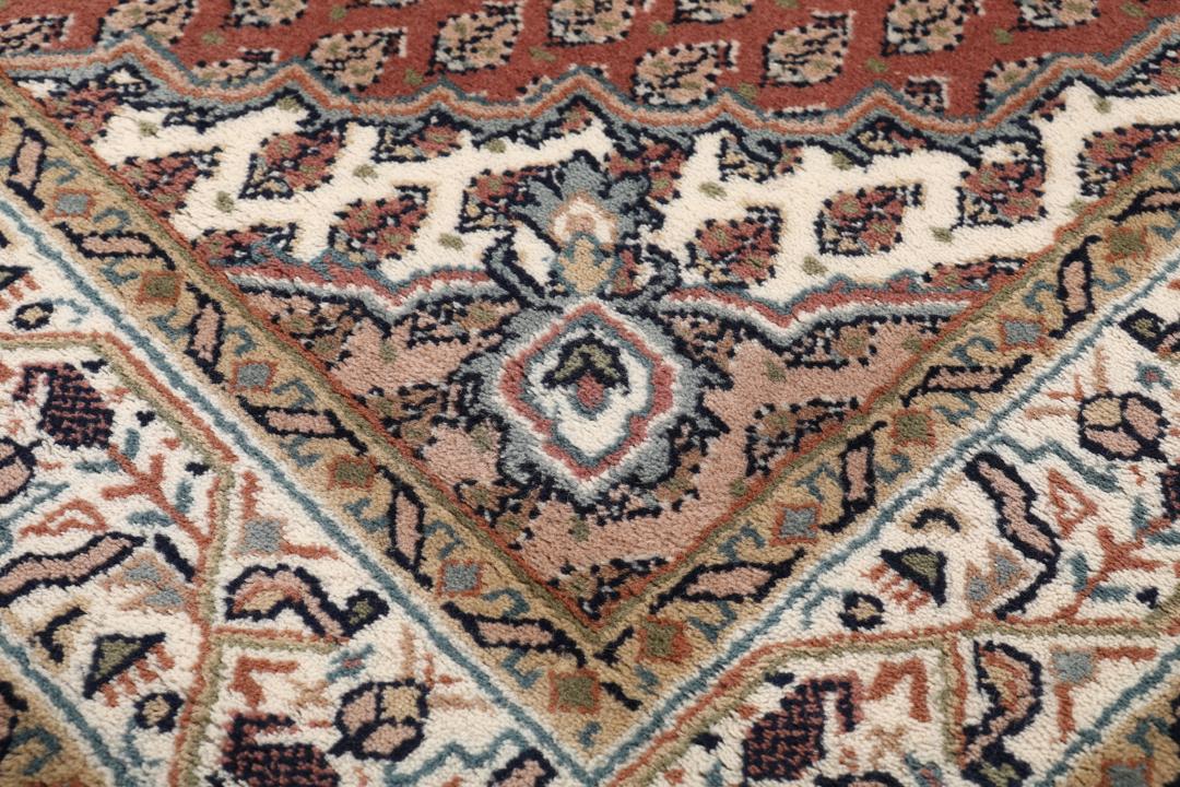 Een handgeknoopt Mir Indo tapijt uit India in donkerrood met een herhalend geometrisch patroon.