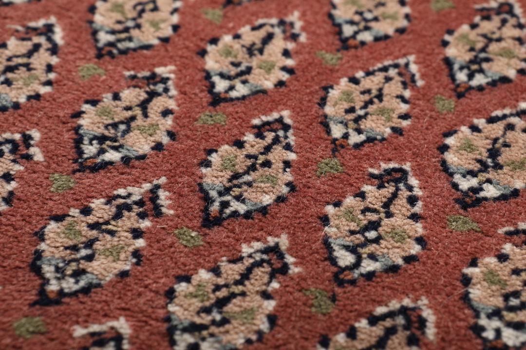 Een handgeknoopt Mir Indo tapijt uit India in donkerrood met een herhalend geometrisch patroon.