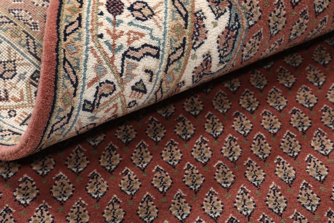 Een handgeknoopt Mir Indo tapijt uit India in donkerrood met een herhalend geometrisch patroon.
