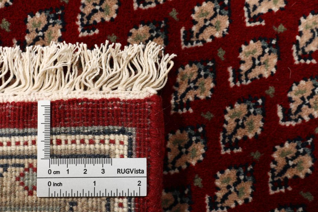 Et håndknyttet Mir Indo-tæppe fra Indien med en rød bund og dekorative kanter