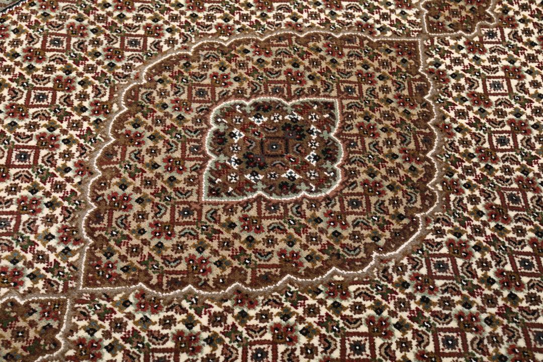Een handgeknoopt Tabriz tapijt uit India met een centraal medaillon in bruine en beige tinten.
