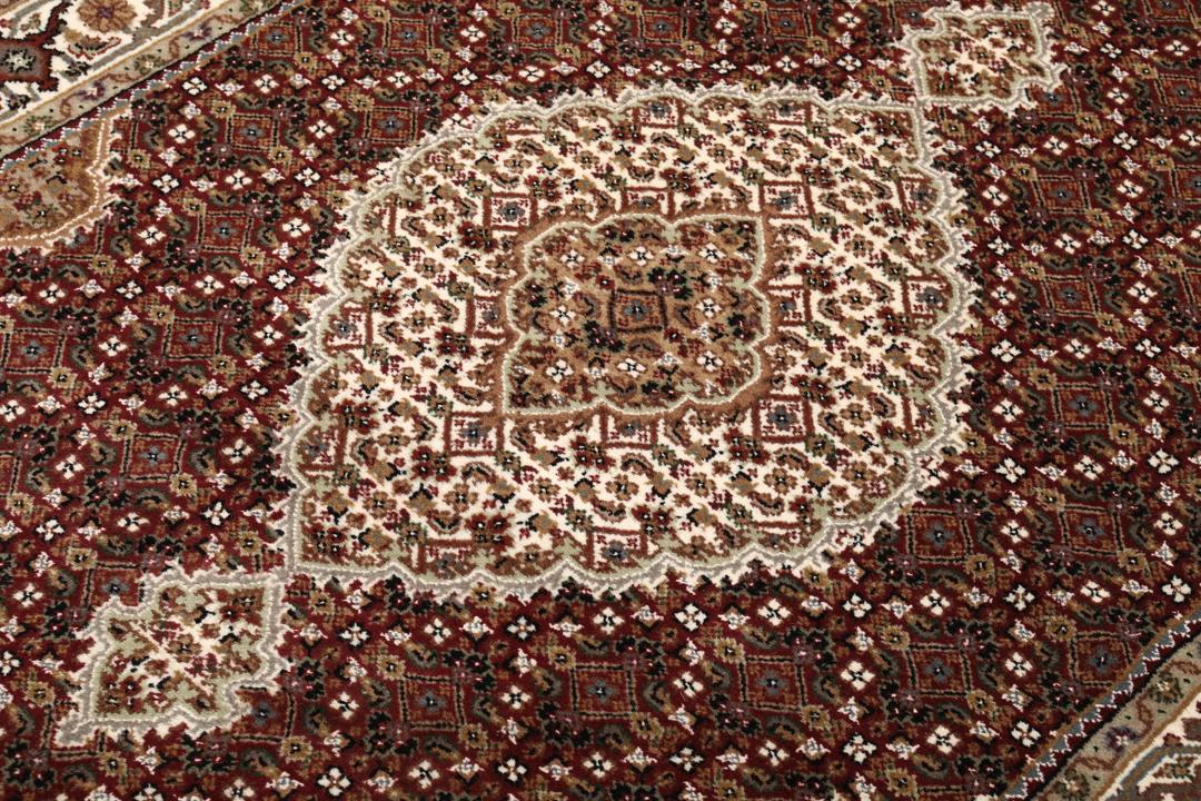 Een handgeknoopt Tabriz-tapijt uit India met een dieprood en beige medaillonpatroon