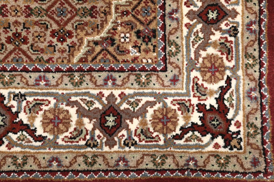 Een handgeknoopt Tabriz-tapijt uit India met een dieprood en beige medaillonpatroon