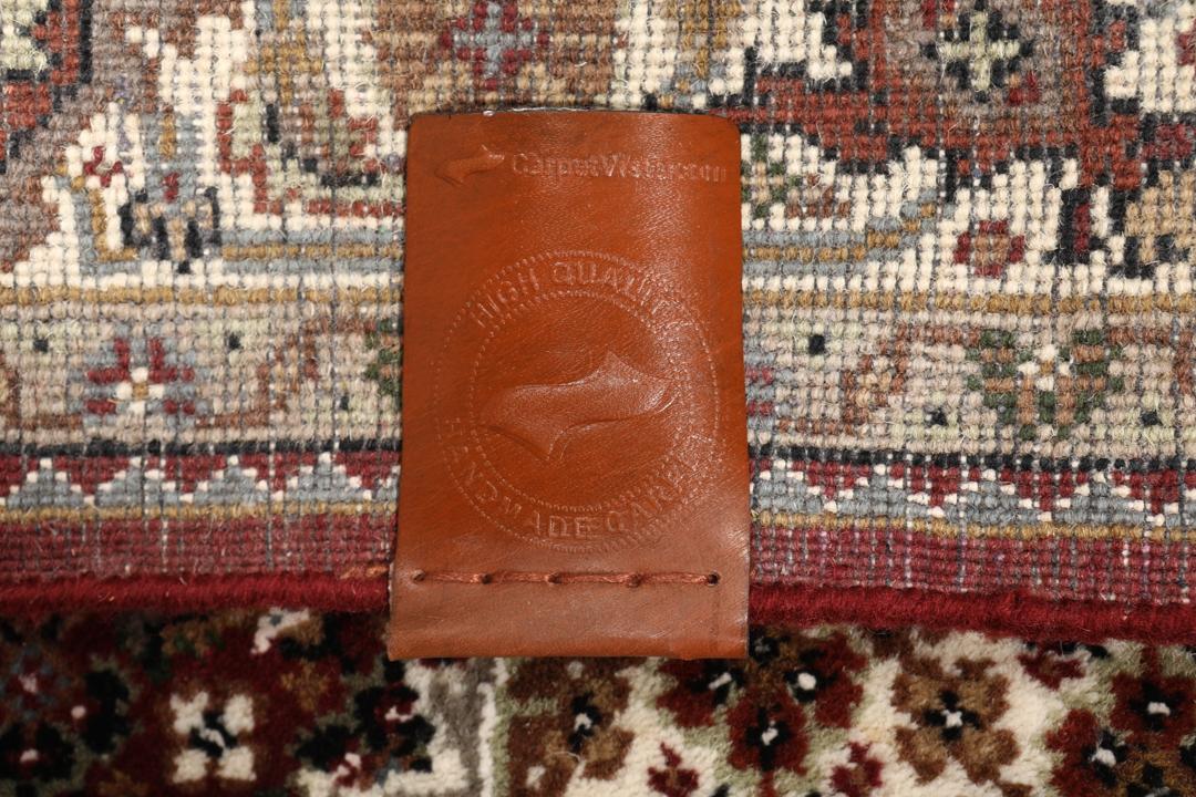 Een handgeknoopt Tabriz-tapijt uit India met een dieprood en beige medaillonpatroon