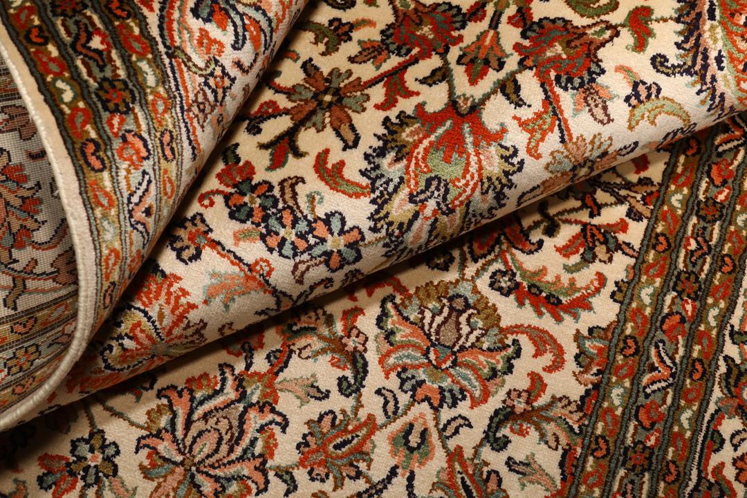 Et håndknyttet Kashmir-silketæppe fra Indien med en beige baggrund og indviklede blomstermotiver.