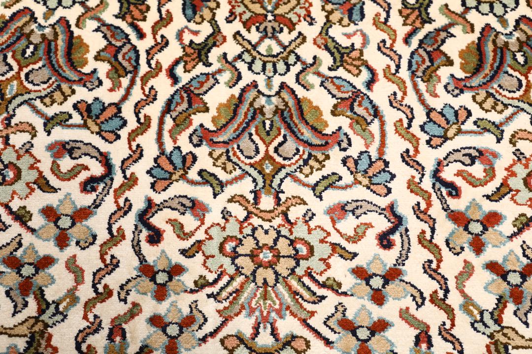 Et håndknyttet Kashmir-silketæppe fra Indien med et indviklet blomstermønster i beige og røde nuancer.