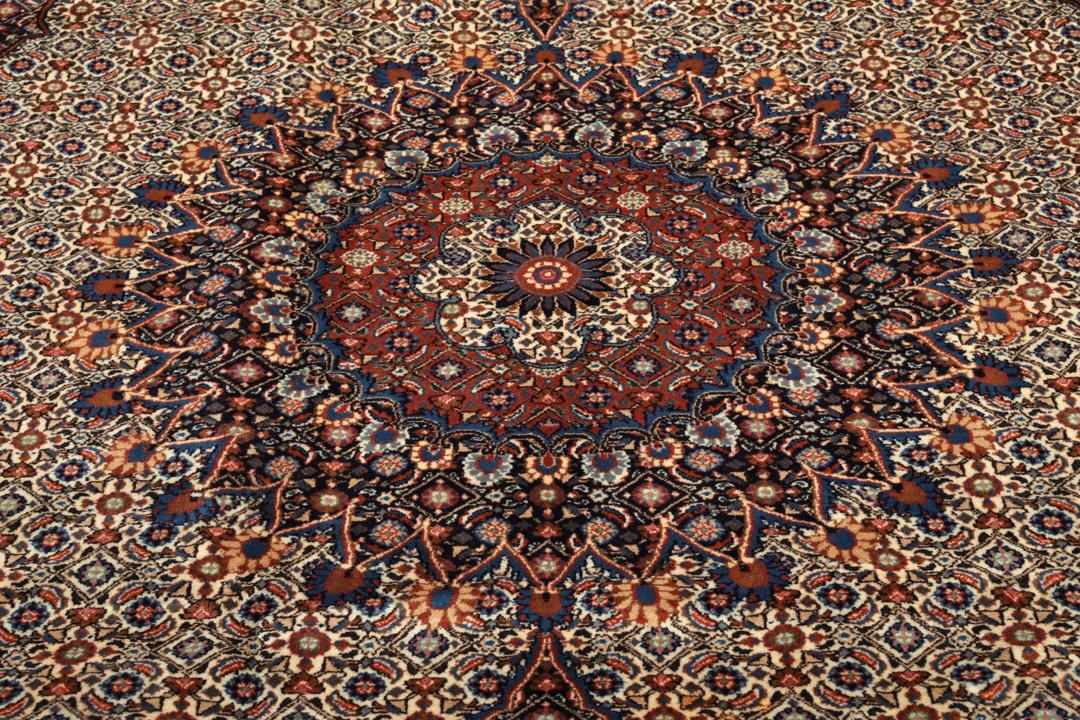 A large rectangular Moud rug from the Middle East featuring a dark-red and beige floral medallion design.