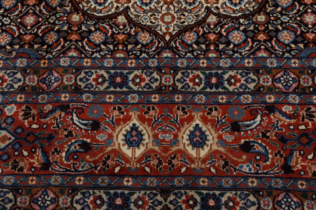 A large rectangular Moud rug from the Middle East featuring a dark-red and beige floral medallion design.