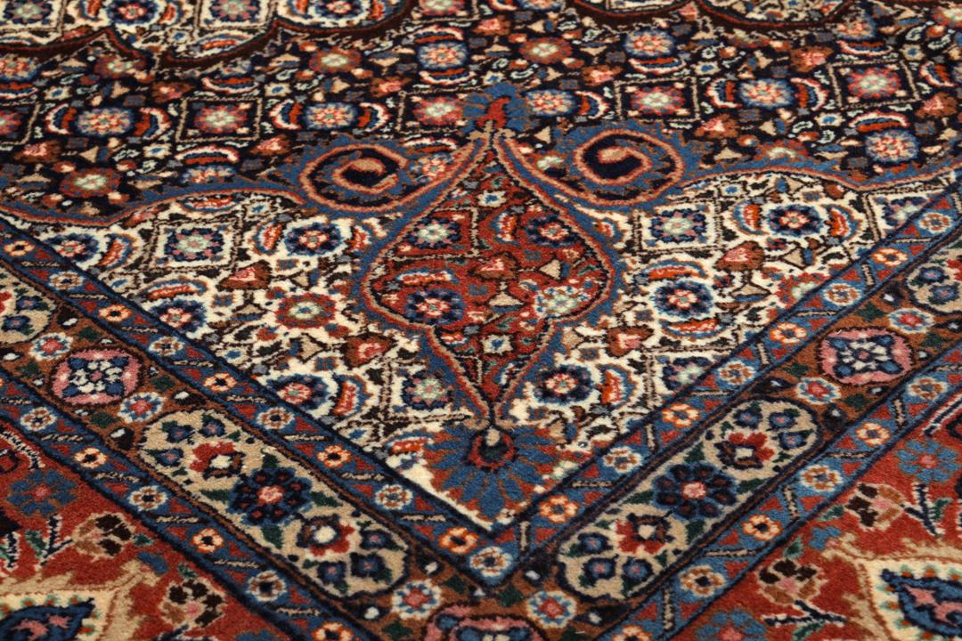 A large rectangular Moud rug from the Middle East featuring a dark-red and beige floral medallion design.