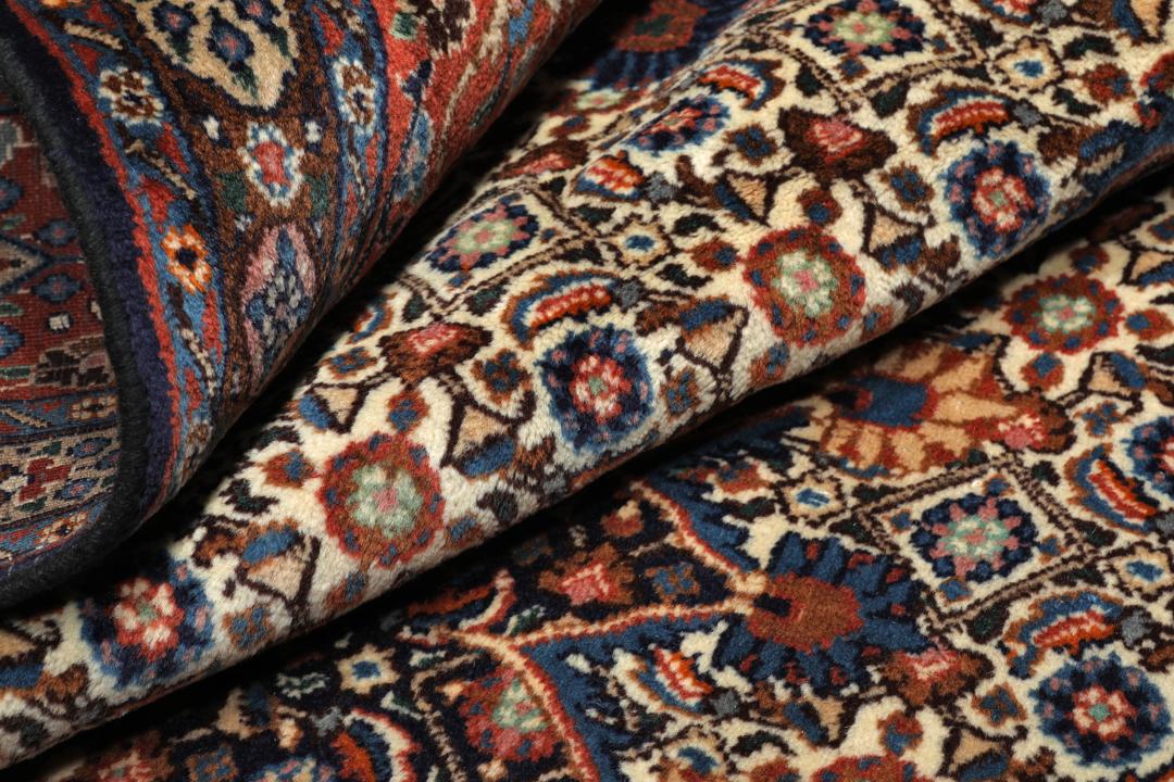 A large rectangular Moud rug from the Middle East featuring a dark-red and beige floral medallion design.