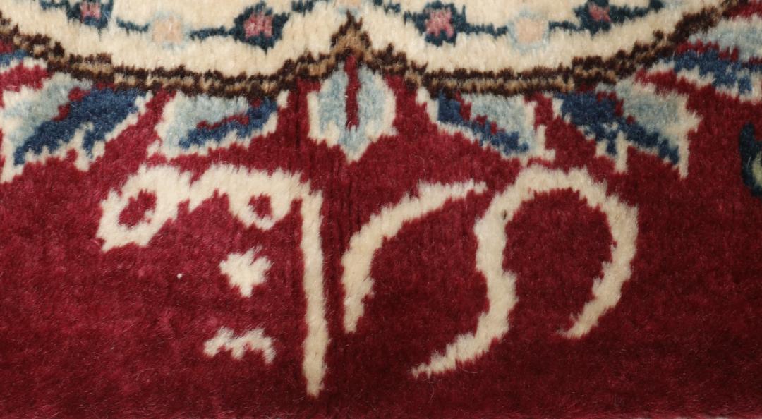 Hand-knotted Mashad rug from the Middle East featuring a dark-red field with intricate floral patterns.