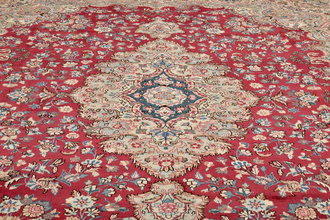 Hand-knotted Mashad rug from the Middle East featuring a dark-red field with intricate floral patterns.