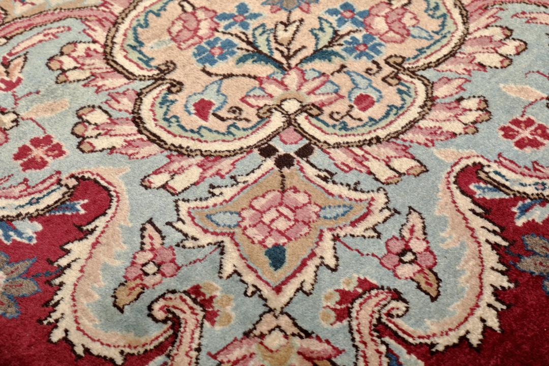 Hand-knotted Mashad rug from the Middle East featuring a dark-red field with intricate floral patterns.