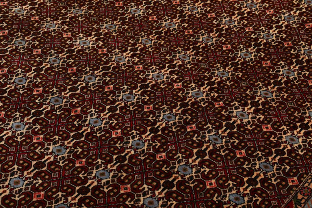 A hand-knotted Senneh rug from the Middle East featuring a dark-red field with geometric motifs.