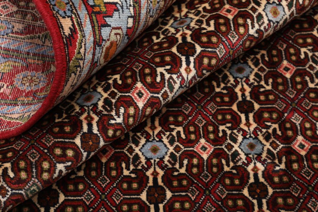 A hand-knotted Senneh rug from the Middle East featuring a dark-red field with geometric motifs.