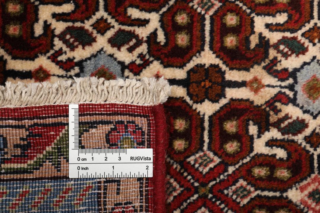 A hand-knotted Senneh rug from the Middle East featuring a dark-red field with geometric motifs.
