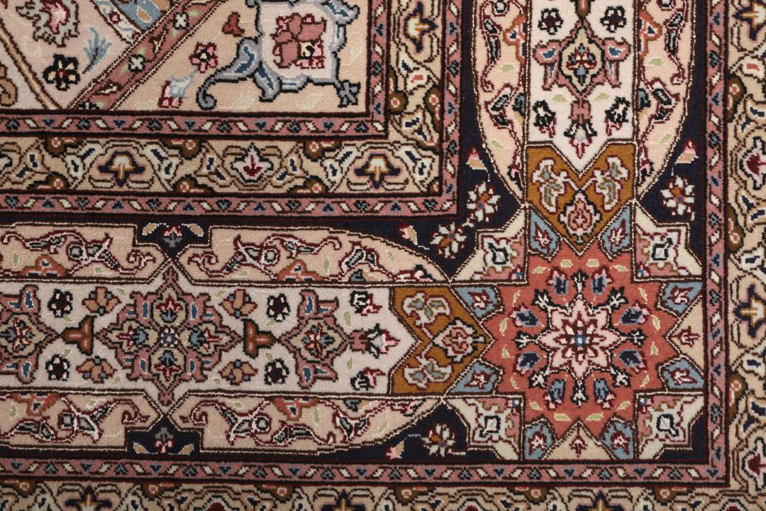 Een vierkant Tabriz-tapijt met een gedetailleerd centraal medaillon in beige en blauwe tinten uit het Midden-Oosten.