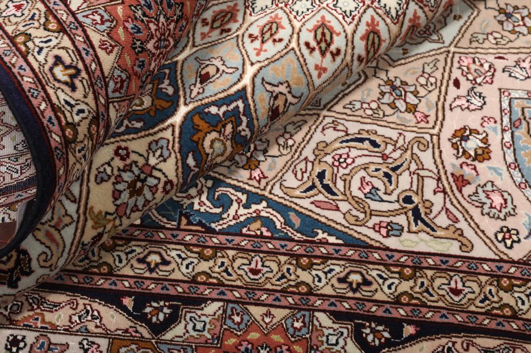 Een vierkant Tabriz-tapijt met een gedetailleerd centraal medaillon in beige en blauwe tinten uit het Midden-Oosten.