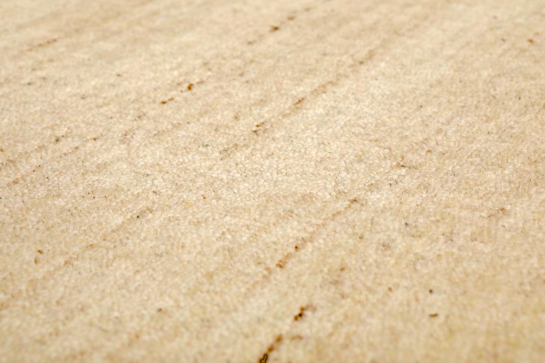 A rectangular rug in natural white and beige with a simple border design.