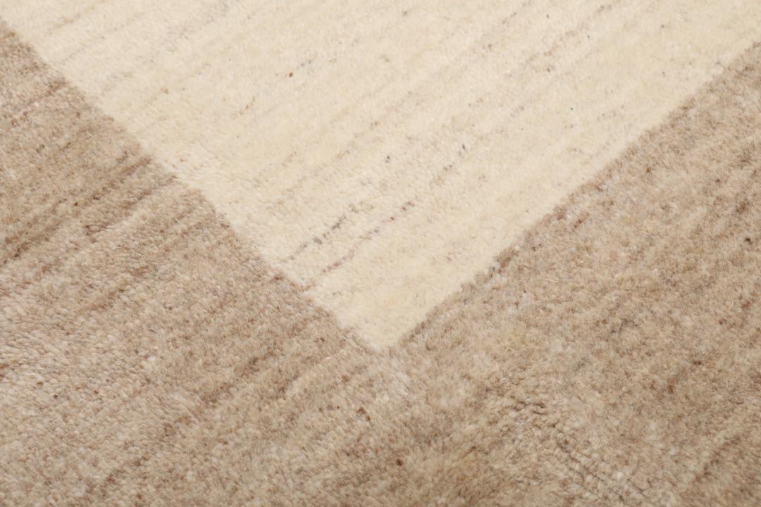 Et rektangulært tæppe i naturhvid og beige med et enkelt kantdesign.