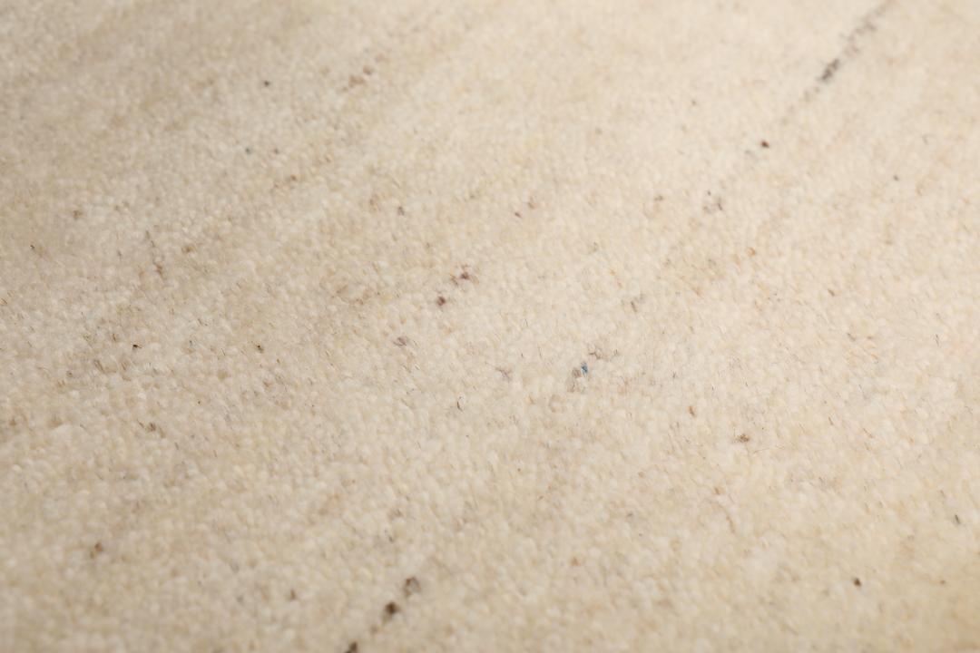 Et rektangulært tæppe i naturhvid og beige med et enkelt kantdesign.