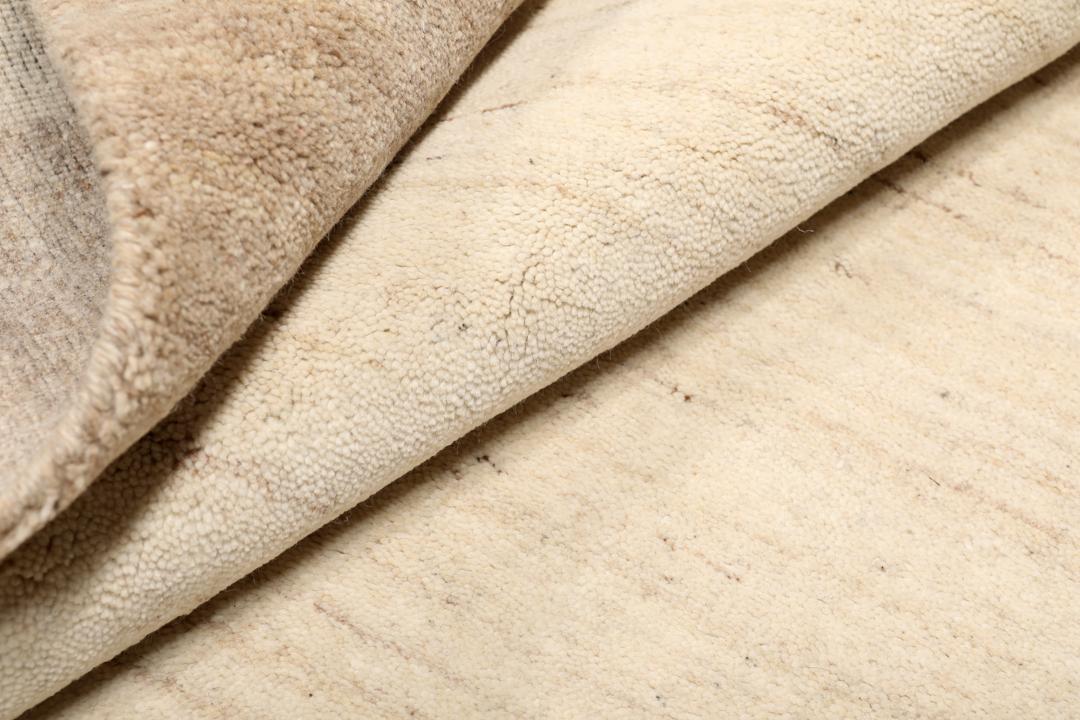 Et rektangulært tæppe i naturhvid og beige med et enkelt kantdesign.