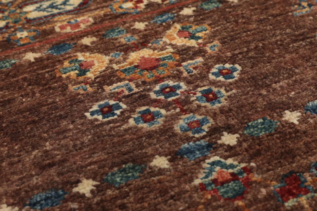 Una alfombra marrón anudada a mano única de Afganistán con intrincados patrones geométricos y florales.