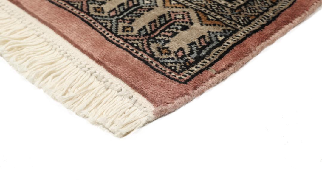 A rectangular Pakistan Bokhara rug with pink field and geometric medallion motifs