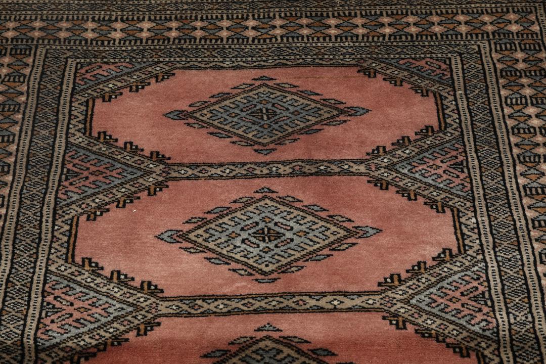 A rectangular Pakistan Bokhara rug with pink field and geometric medallion motifs
