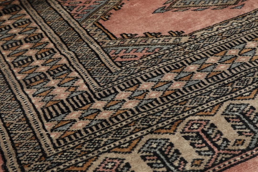 A rectangular Pakistan Bokhara rug with pink field and geometric medallion motifs