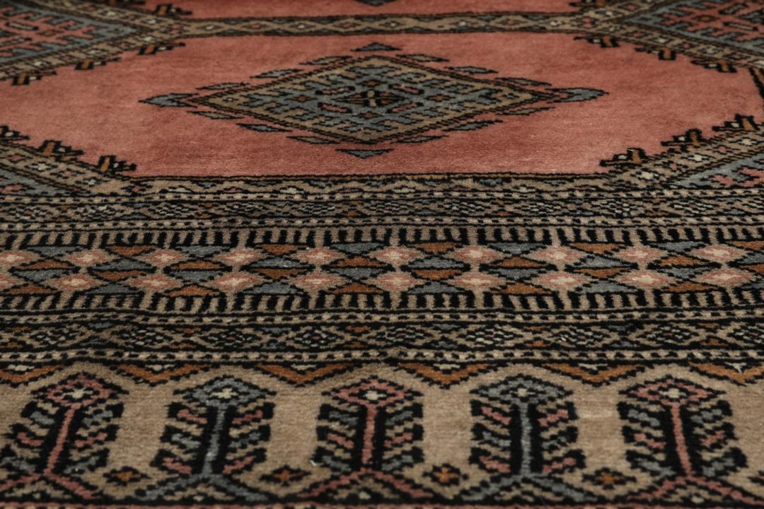 A rectangular Pakistan Bokhara rug with pink field and geometric medallion motifs