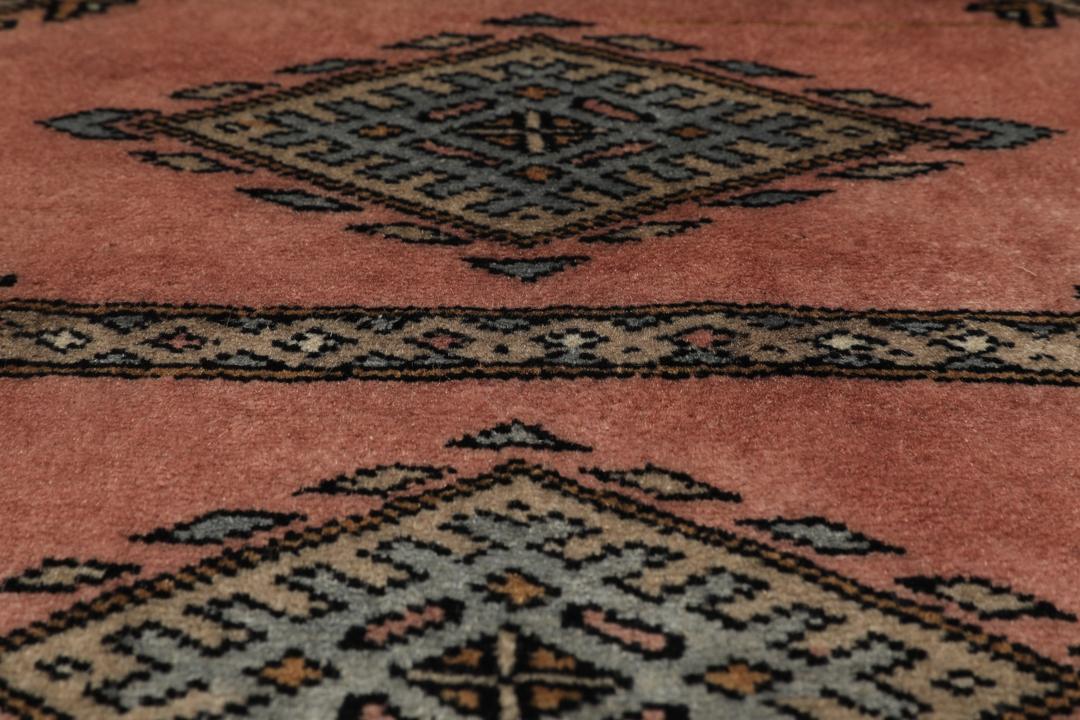 A rectangular Pakistan Bokhara rug with pink field and geometric medallion motifs