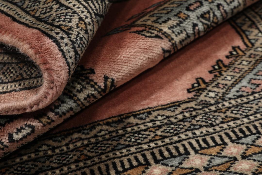 A rectangular Pakistan Bokhara rug with pink field and geometric medallion motifs