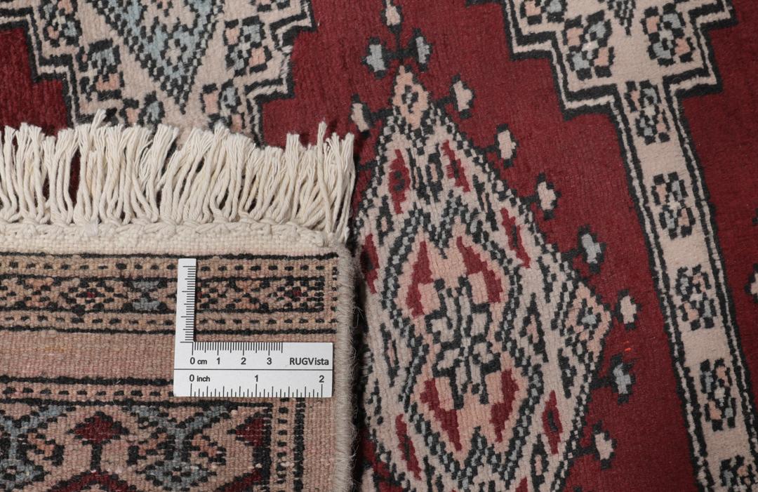 A rectangular hand-knotted Pakistan Bokhara rug with a deep red field and geometric motifs.