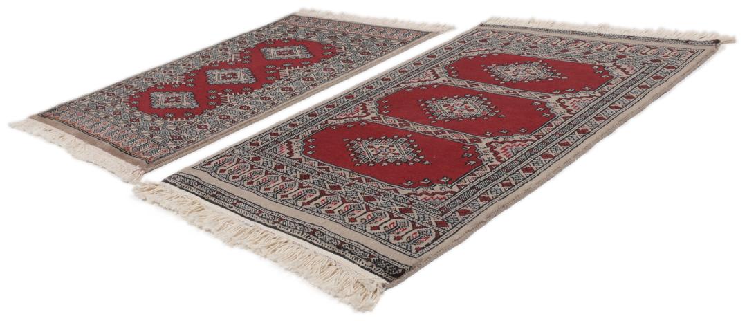 A red and beige hand-knotted Pakistan Bokhara rug with traditional geometric motifs.