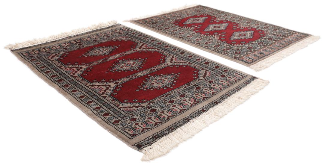 A red and beige hand-knotted Pakistan Bokhara rug with traditional geometric motifs.