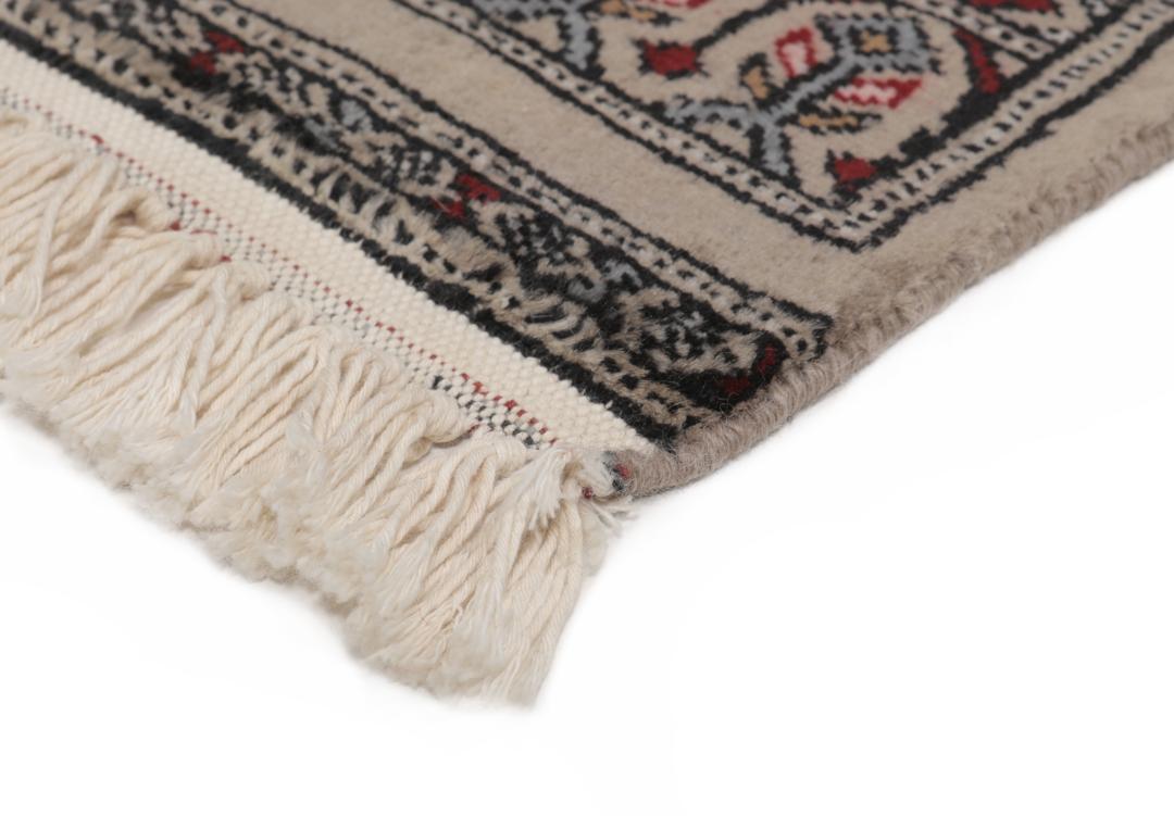 A red and beige hand-knotted Pakistan Bokhara rug with traditional geometric motifs.