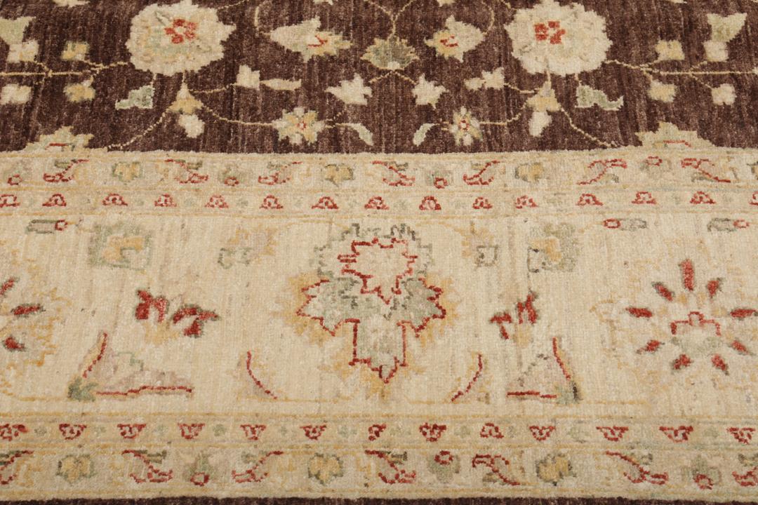 A hand-knotted Afghan rug with a dark brown field and ornate floral patterns.