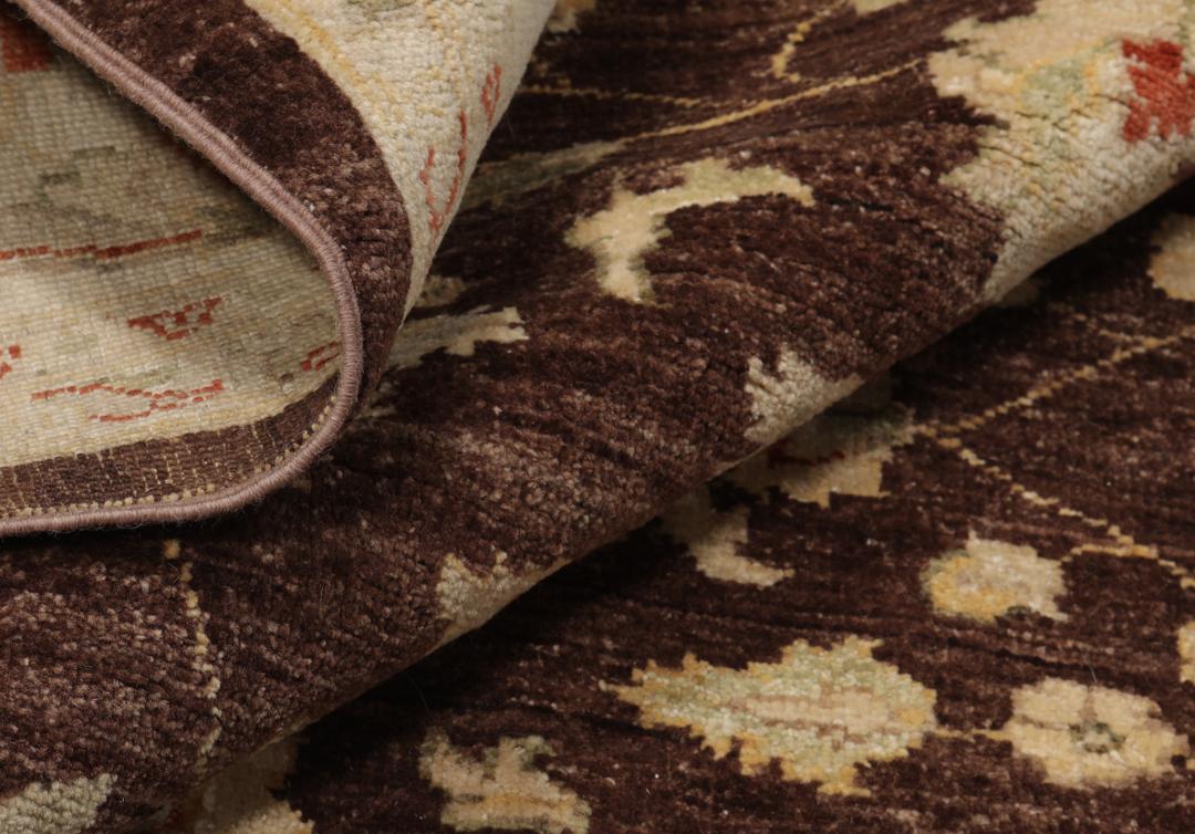 A hand-knotted Afghan rug with a dark brown field and ornate floral patterns.
