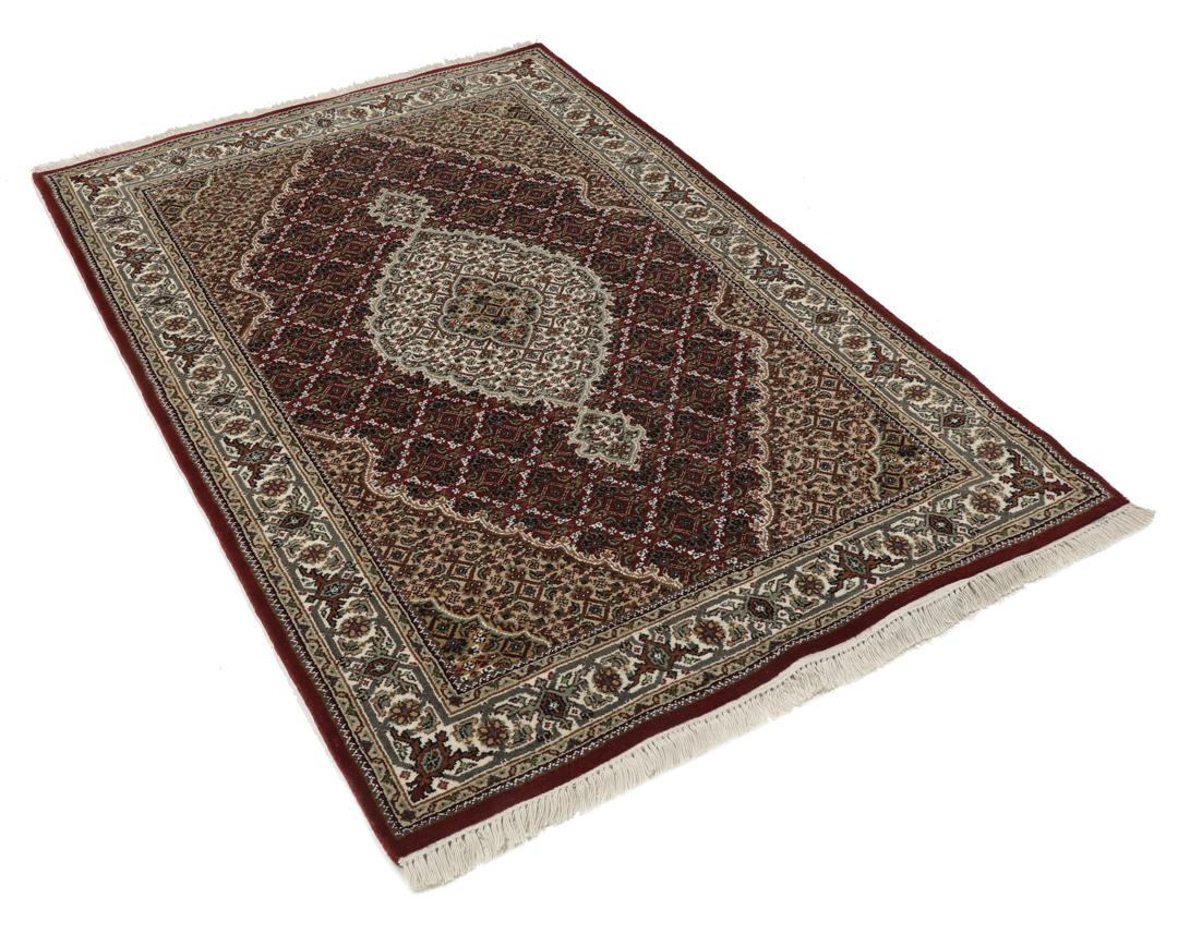 Een handgeknoopt Tabriz-tapijt uit India met een centraal medaillon in dieprood en crème.