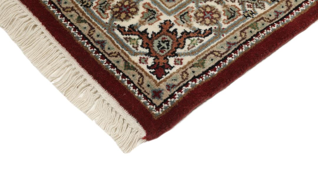 Een handgeknoopt Tabriz-tapijt uit India met een centraal medaillon in dieprood en crème.