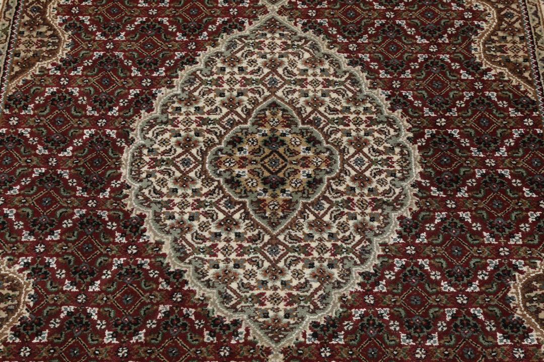 Een handgeknoopt Tabriz-tapijt uit India met een centraal medaillon in dieprood en crème.