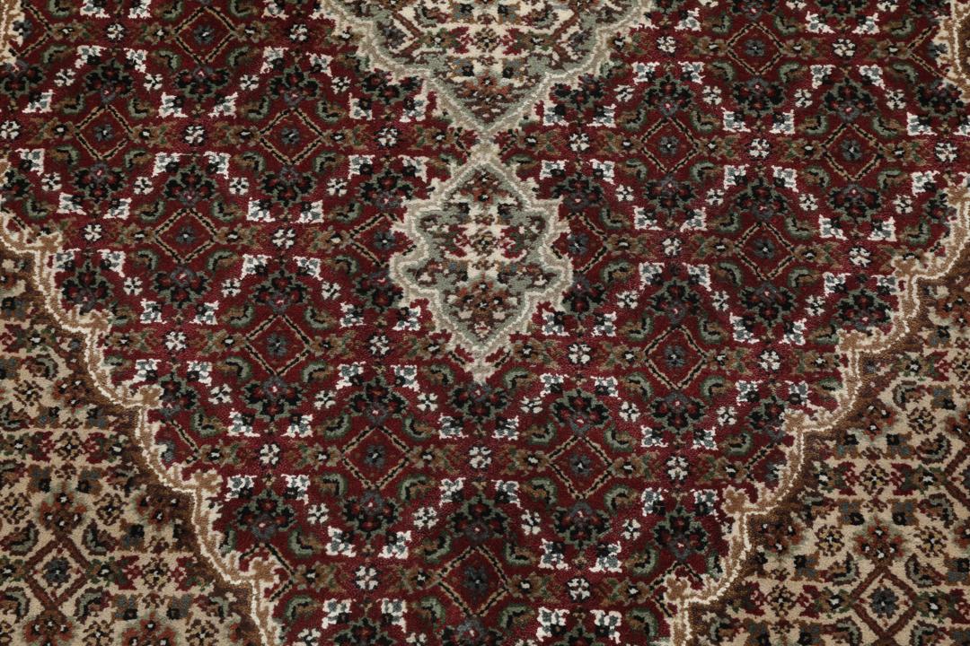 Een handgeknoopt Tabriz-tapijt uit India met een centraal medaillon in dieprood en crème.