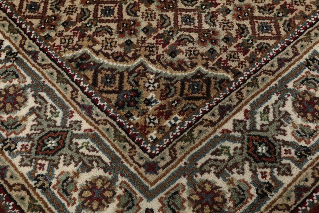 Een handgeknoopt Tabriz-tapijt uit India met een centraal medaillon in dieprood en crème.