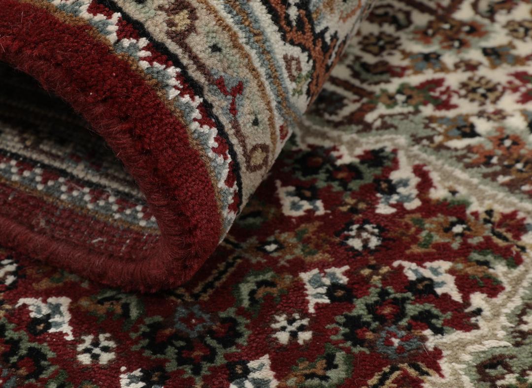Een handgeknoopt Tabriz-tapijt uit India met een centraal medaillon in dieprood en crème.