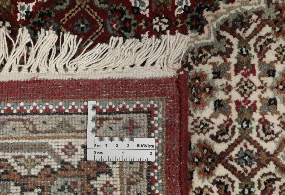 Een handgeknoopt Tabriz-tapijt uit India met een centraal medaillon in dieprood en crème.